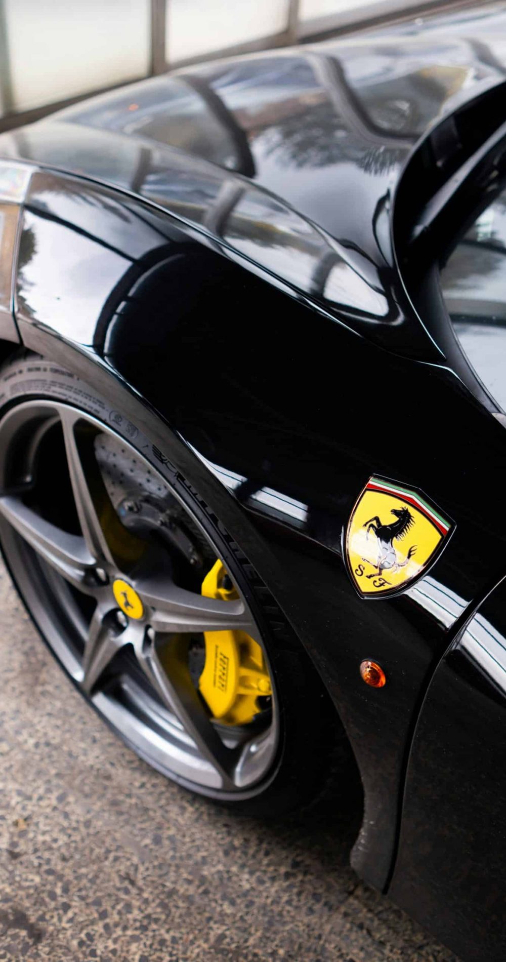 Detailed view of a sleek black sports car with a focus on its wheel and iconic logo.